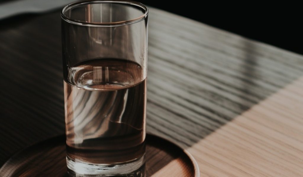 Tranquil Solitude_ Half-Full Glass of Water on Wooden Surface