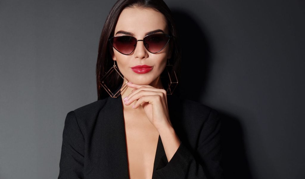 Beautiful woman wearing jacket and sunglasses on black background